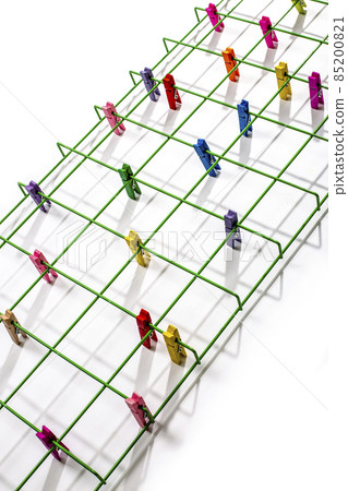 Still life with green metal lattice and multi-colored clothespins Still life with green metal lattice and multi-colored clothespins 85200821