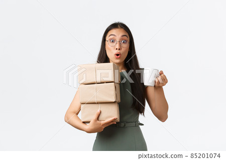 Young female asian assistant, office lady carry delivery to boss office and bring coffee mug, holding piles of boxes and cup with drink, standing white background excited Young female asian assistant, office lady carry delivery to boss office and bring coffee mug, holding piles of boxes and cup with drink, standing white background excited 85201074