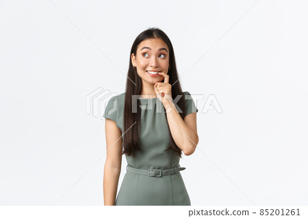 Small business owners, women entrepreneurs concept. Tempting and excited cute asian woman biting finger and looking with desire, thinking, making decision, standing white background 85201261