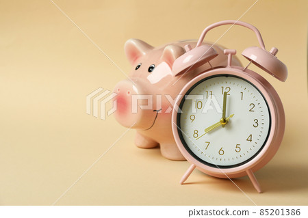 Piggy bank and pink alarm clock on beige background 85201386