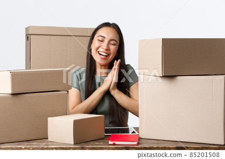 Small business owners, startup and e-commerce concept. Cheerful asian businesswoman rejoicing, clap hands happy as working home, selling online, packing boxes with client orders, white background Small business owners, startup and e-commerce concept. Cheerful asian businesswoman rejoicing, clap hands happy as working home, selling online, packing boxes with client orders, white background 85201508