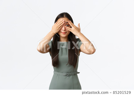 Small business owners, women entrepreneurs concept. Excited asian female in dress, smiling intrigued as shut eyes and peeking through fingers, anticipating surprise, standing white background Small business owners, women entrepreneurs concept. Excited asian female in dress, smiling intrigued as shut eyes and peeking through fingers, anticipating surprise, standing white background 85201529