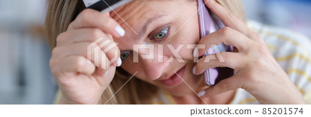 Upset woman in stress holds bank card and talks on phone Upset woman in stress holds bank card and talks on phone 85201574