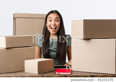 Small business owners, startup and e-commerce concept. Excited happy asian businesswoman receive big order, packing boxes for clients, shipping parcels, working from home in online store Small business owners, startup and e-commerce concept. Excited happy asian businesswoman receive big order, packing boxes for clients, shipping parcels, working from home in online store 85201576