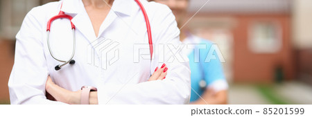 Doctors veterinarians stand confidently with folded hands on background of farm Doctors veterinarians stand confidently with folded hands on background of farm 85201599