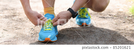 Man shoelaces laces on sports fashion sneakers in park 85201621