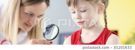 Dermatologist examines little girl hand through magnifying glass Dermatologist examines little girl hand through magnifying glass 85201633