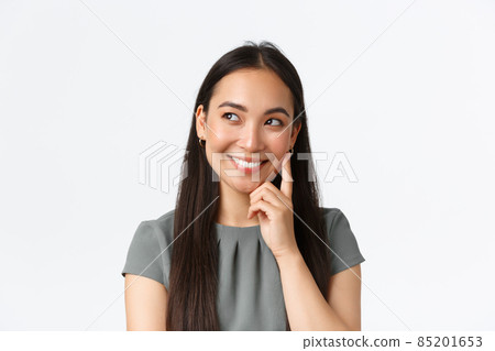 Close-up of creative and dreamy smiling pretty asian woman thinking, imaging something interesting in mind, looking left and touching cheek, pondering plan, standing white background Close-up of creative and dreamy smiling pretty asian woman thinking, imaging something interesting in mind, looking left and touching cheek, pondering plan, standing white background 85201653