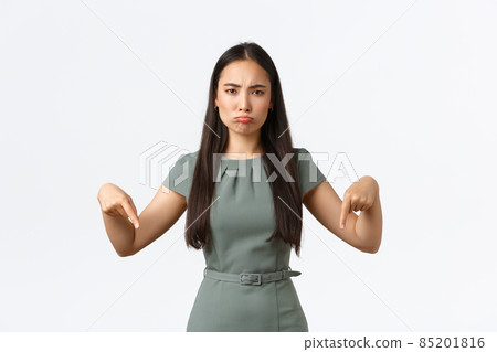 Small business owners, women entrepreneurs concept. Disappointed or offended beautiful asian woman in dress, complaining something bad, pointing fingers down and pouting displeased 85201816