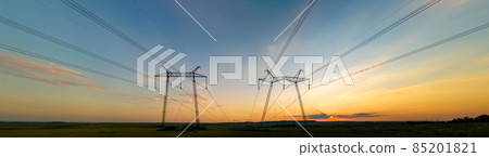 Dark silhouette of high voltage towers with electric power lines at sunrise. 85201821
