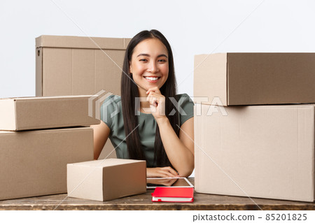 Small business owners, startup and e-commerce concept. Successful asian female entrepreneur with online shop, selling in internet, sending boxes with orders, packing items for shipping, smiling Small business owners, startup and e-commerce concept. Successful asian female entrepreneur with online shop, selling in internet, sending boxes with orders, packing items for shipping, smiling 85201825