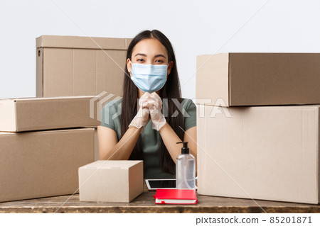 Small business owners, e-commerce and covid-19 preventing virus concept. Asian businesswoman with online store sit medical mask and gloves, using hand sanitizer while packing customer orders Small business owners, e-commerce and covid-19 preventing virus concept. Asian businesswoman with online store sit medical mask and gloves, using hand sanitizer while packing customer orders 85201871