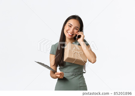 Friendly smiling and polite asian female shop owner, managing small business, carry clipboard and package box for shipping, answering clients call, talking with customer, checking info for delivery Friendly smiling and polite asian female shop owner, managing small business, carry clipboard and package box for shipping, answering clients call, talking with customer, checking info for delivery 85201896