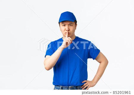 Angry and bossy serious-looking asian courier telling keep quiet, scolding employees misbehaviour at work. Delivery guy shushing with finger pressed to lips, lookins disappointed at camera Angry and bossy serious-looking asian courier telling keep quiet, scolding employees misbehaviour at work. Delivery guy shushing with finger pressed to lips, lookins disappointed at camera 85201961