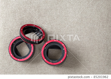 Close-up of macro rings, camera adapters on light cloth copy space background. Modern technology and photography equipment concept. Close-up of macro rings, camera adapters on light cloth copy space background. Modern technology and photography equipment concept. 85201962