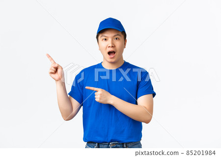 Amazed and impressed asian courier in blue uniform making announcement, gasping amazed and pointing upper left corner at something awesome. Delivery guy demonstrate banner Amazed and impressed asian courier in blue uniform making announcement, gasping amazed and pointing upper left corner at something awesome. Delivery guy demonstrate banner 85201984