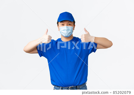 Contactless delivery, covid-19 shipping, preventing virus concept. Smiling confident asian courier in medical mask and gloves showing thumbs-up guarantee safe shipment during coronavirus Contactless delivery, covid-19 shipping, preventing virus concept. Smiling confident asian courier in medical mask and gloves showing thumbs-up guarantee safe shipment during coronavirus 85202079