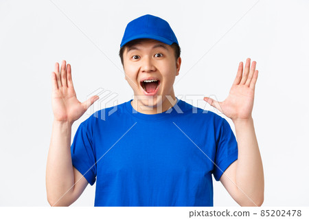 Online shopping, fast shipping, employees and home delivery concept. Rejoicing smiling, happy asian male courier in blue uniform, clap hands, making big announcement, standing white background Online shopping, fast shipping, employees and home delivery concept. Rejoicing smiling, happy asian male courier in blue uniform, clap hands, making big announcement, standing white background 85202478
