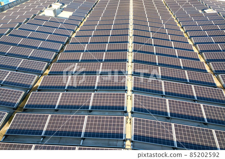 Aerial view of many photo voltaic solar panels mounted of industrial building roof. Aerial view of many photo voltaic solar panels mounted of industrial building roof. 85202592