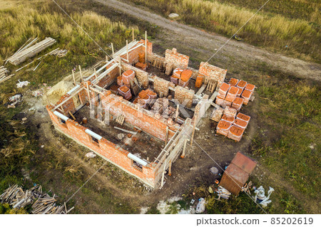 Aerial view of building site for future brick house, concrete foundation floor and stacks of yellow clay bricks for construction. 85202619