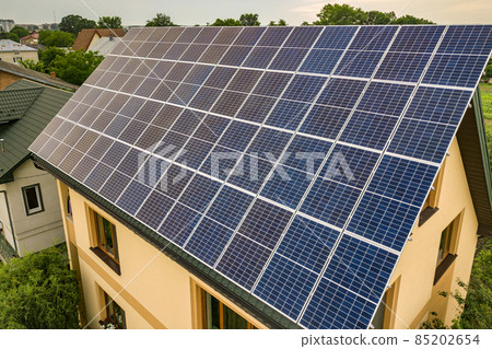 Aerial top view of new modern residential house cottage with blue shiny solar photo voltaic panels system on roof. Renewable ecological green energy production concept. 85202654