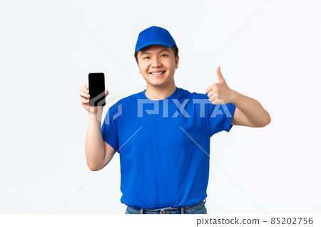 Technology, online shopping and shipping concept. Happy and satisfied asian delivery man in blue courier uniform smiling pleased, show thumbs-up and mobile phone screen, recommend tracking app Technology, online shopping and shipping concept. Happy and satisfied asian delivery man in blue courier uniform smiling pleased, show thumbs-up and mobile phone screen, recommend tracking app 85202756