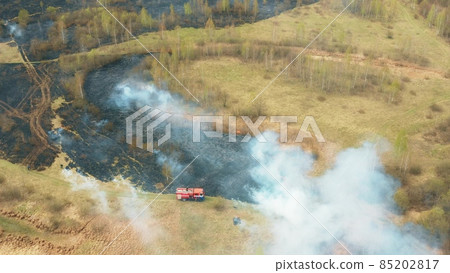 4K Aerial View Spring Dry Grass Burns During Drought Hot Weather. Bush Fire And Smoke. Fire Engine, Fire Truck On Firefighting Operation. Wild Open Fire Destroys Grass. Ecological Problem Air 85202817
