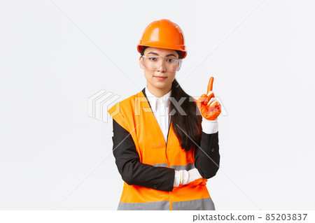 Safety first. Serious, smiling female asian construction engineer, industrial woman showing finger at telling rules on enterprise, wearing protective glasses, helmet and gloves, white background Safety first. Serious, smiling female asian construction engineer, industrial woman showing finger at telling rules on enterprise, wearing protective glasses, helmet and gloves, white background 85203837