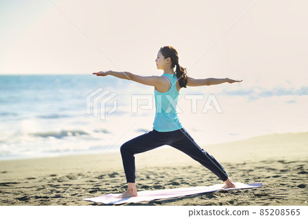 Young woman doing yoga on the beach 85208565