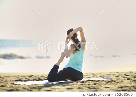Young woman doing yoga on the beach 85208566