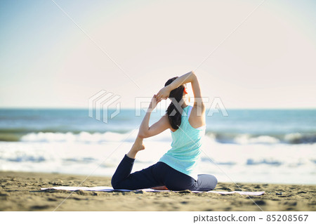 Young woman doing yoga on the beach Young woman doing yoga on the beach 85208567