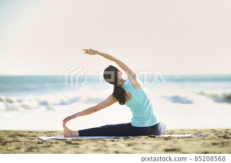 Young woman doing yoga on the beach 85208568