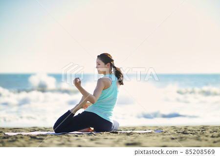 Young woman doing yoga on the beach 85208569