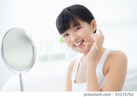 Beautiful face of young asian woman with happy smiling and touch cheek looking mirror. Beautiful face of young asian woman with happy smiling and touch cheek looking mirror. 85210762