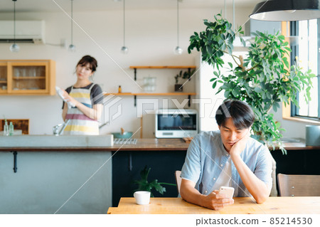 A woman who suspects a man looking at a smartphone A woman who suspects a man looking at a smartphone 85214530