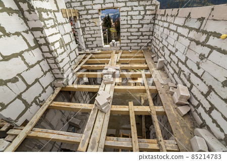 Interior of future cottage, energy saving walls of large white hollow foam insulation blocks and temporary wooden scaffolding frame. Construction, masonry, modern technology concept. 85214783