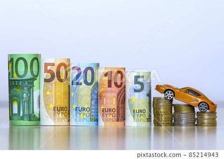 Blurred row of rolled hundred, fifty, twenty, ten and five new euro banknotes and pile of coins with yellow toy expensive sport car. Symbol of financial prosperity, vehicle sale and purchase. 85214943
