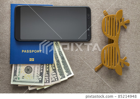 Black cellphone, money American dollars banknotes bills, passport and toy funny sunglasses on copy space background, top view. Traveling, journey, vacation planning, adventure and wanderlust concept. 85214948