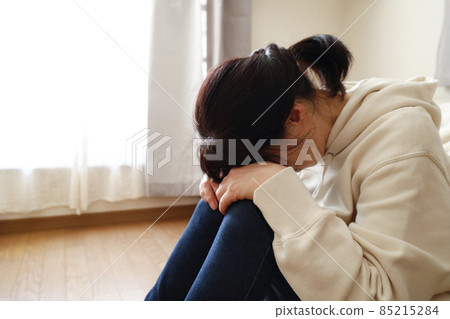 一個女人坐在房間的地板上，臉朝下躺著 85215284
