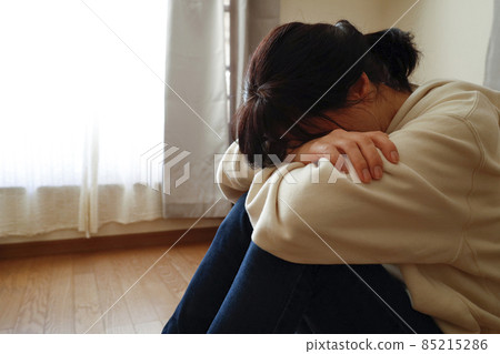 一個女人坐在房間的地板上，臉朝下躺著 85215286