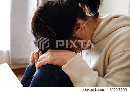 一個女人坐在房間的地板上,臉朝下躺著 一個女人坐在房間的地板上,臉朝下躺著 85215293