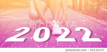 Cropped image of sports women hands tying laces off white sneakers outdoor for the run training, healthy exercise workout concept 85216337