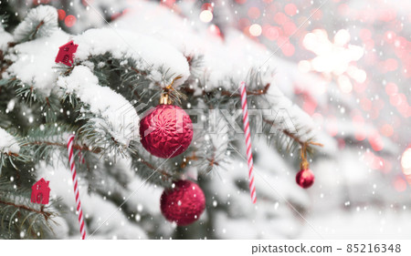 Beautiful Christmas tree outdoor with pink xmas balls, snow, lights bokeh around, and snow falling, Christmas atmosphere. Beautiful Christmas tree outdoor with pink xmas balls, snow, lights bokeh around, and snow falling, Christmas atmosphere. 85216348