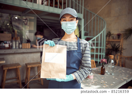 Portrait of young woman in face mask working indoors 85216359