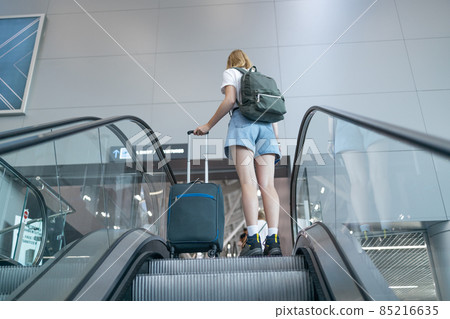 Traveler woman with luggage in airport standing on escalator go to gate for journey. 85216635