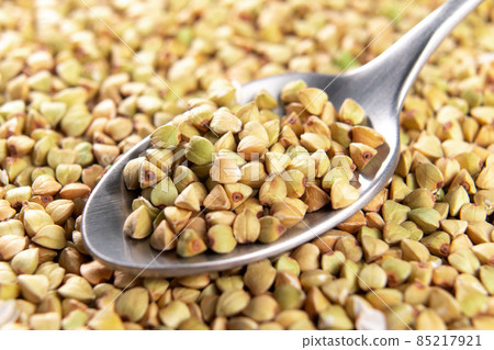 Raw green buckwheat in spoon. Uncooked grains. Macro Raw green buckwheat in spoon. Uncooked grains. Macro 85217921