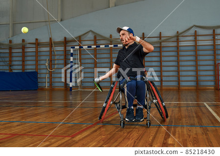 Young man in wheelchair playing tennis on court 85218430