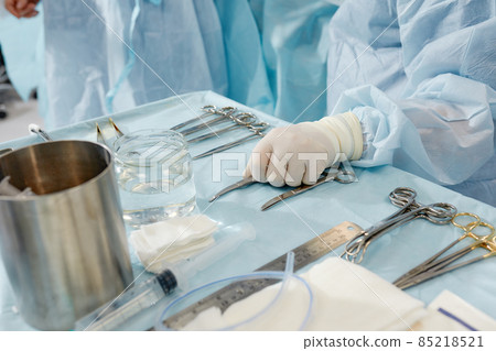 scrub nurse preparing medical instruments for operation 85218521