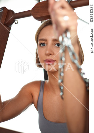 beautiful girl trains on the modern reformer simulator to work out deep muscles, the modernized reformer equipment for Pilates and yoga. beautiful girl trains on the modern reformer simulator to work out deep muscles, the modernized reformer equipment for Pilates and yoga. 85218588