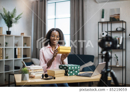 African woman recording video while unpacking gift boxes African woman recording video while unpacking gift boxes 85219059